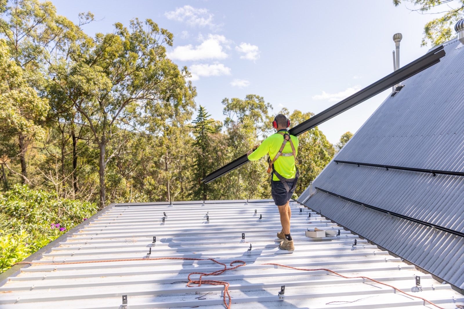 Solar installer carrying rail on a residential roof